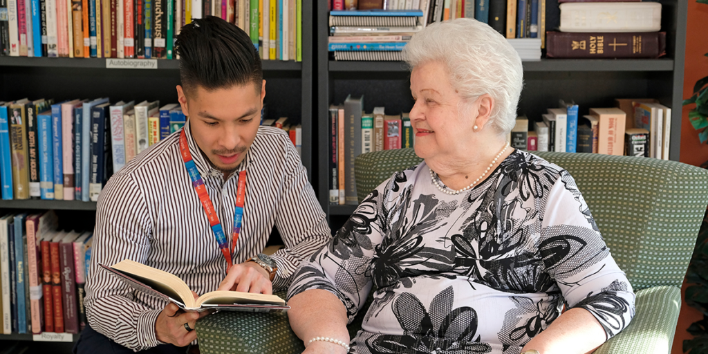 A resident of the Cardinal Ambrozic Houses of Providence reads with a volunteer