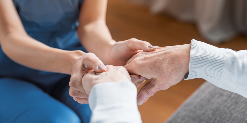 A long term care worker holds the hands of a senior woman
